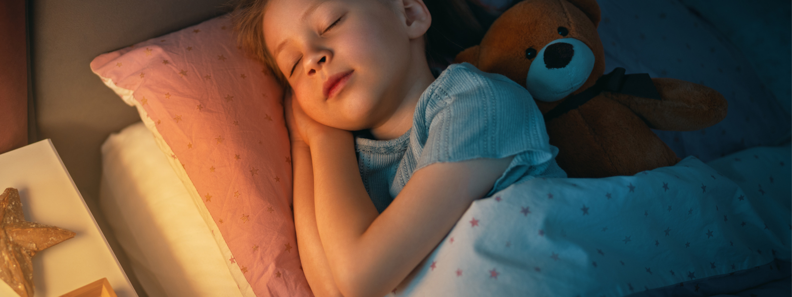 Liten flicka som sover tryggt med en nallebjörn bredvid sig i sängen – lugn natt med tygblöja från Time Ahead Sweden