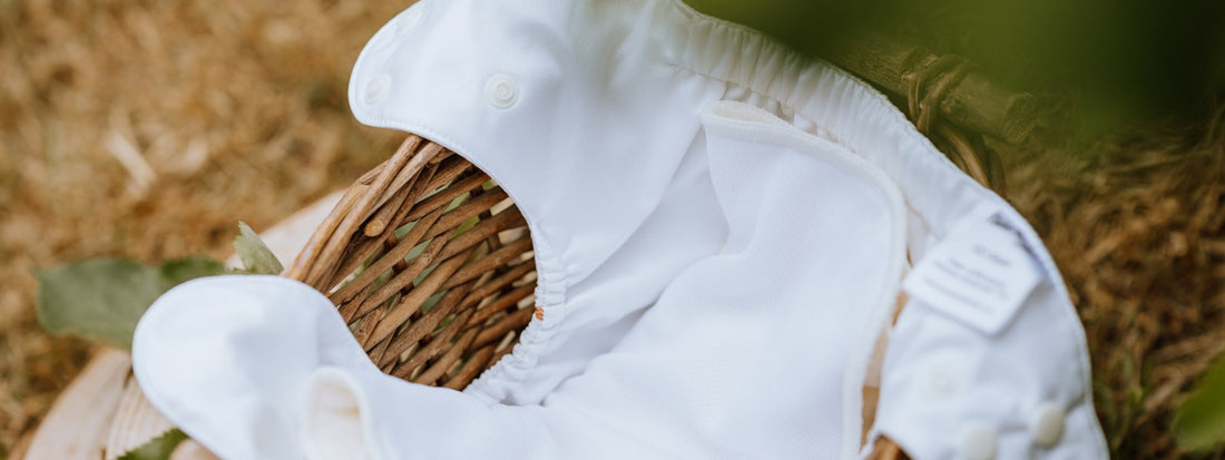 White Cover/All-in-one cloth nappy from Time Ahead in a woven basket outdoors