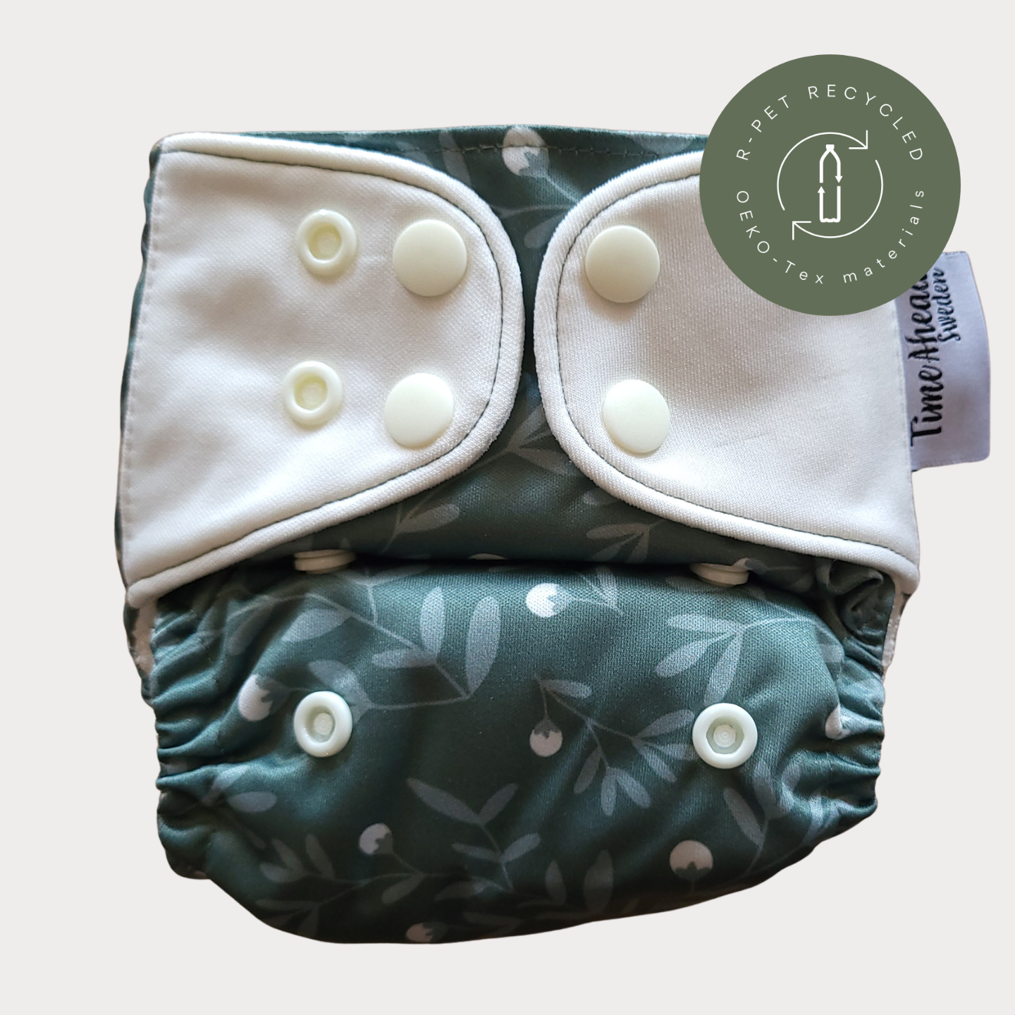 Cloth Nappy Newborn all-in-one 2–6 kg in the Humleblomster grön pattern, shown from the front with white snap tabs.