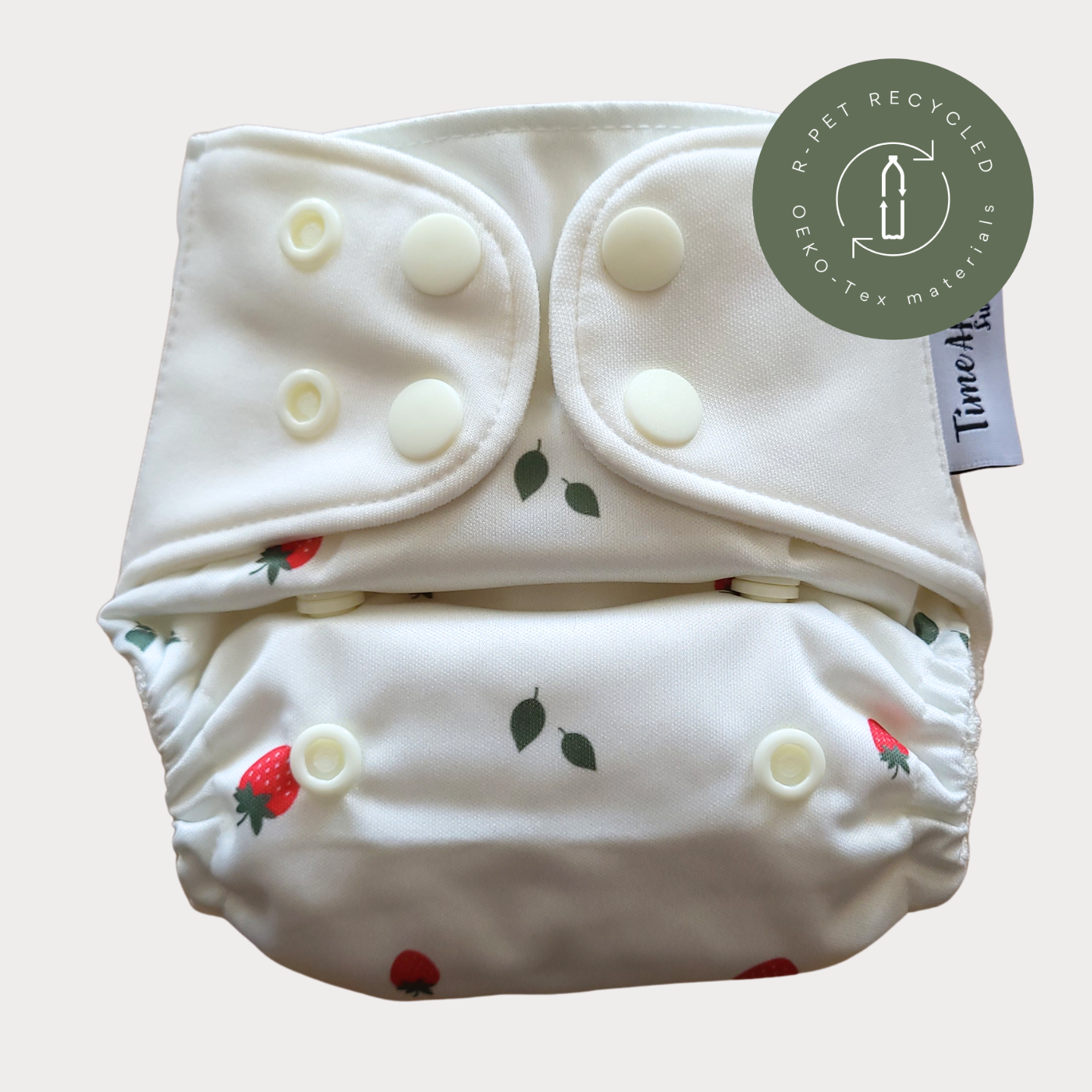 Cloth Nappy Newborn all-in-one 2–6 kg in the Smultron pattern, shown from the front with white snap tabs.