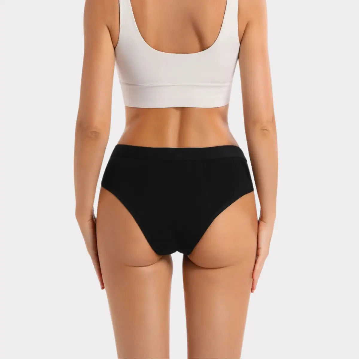 En kvinna visar upp en vit sport-bh och svarta bikinitrosor.