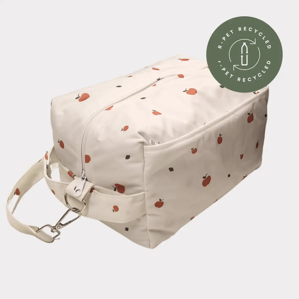 Krämfärgad toalettväska med ett lekfullt mönster av små röda äpplen och svarta prickar, med robust blixtlås och justerbart axelband.