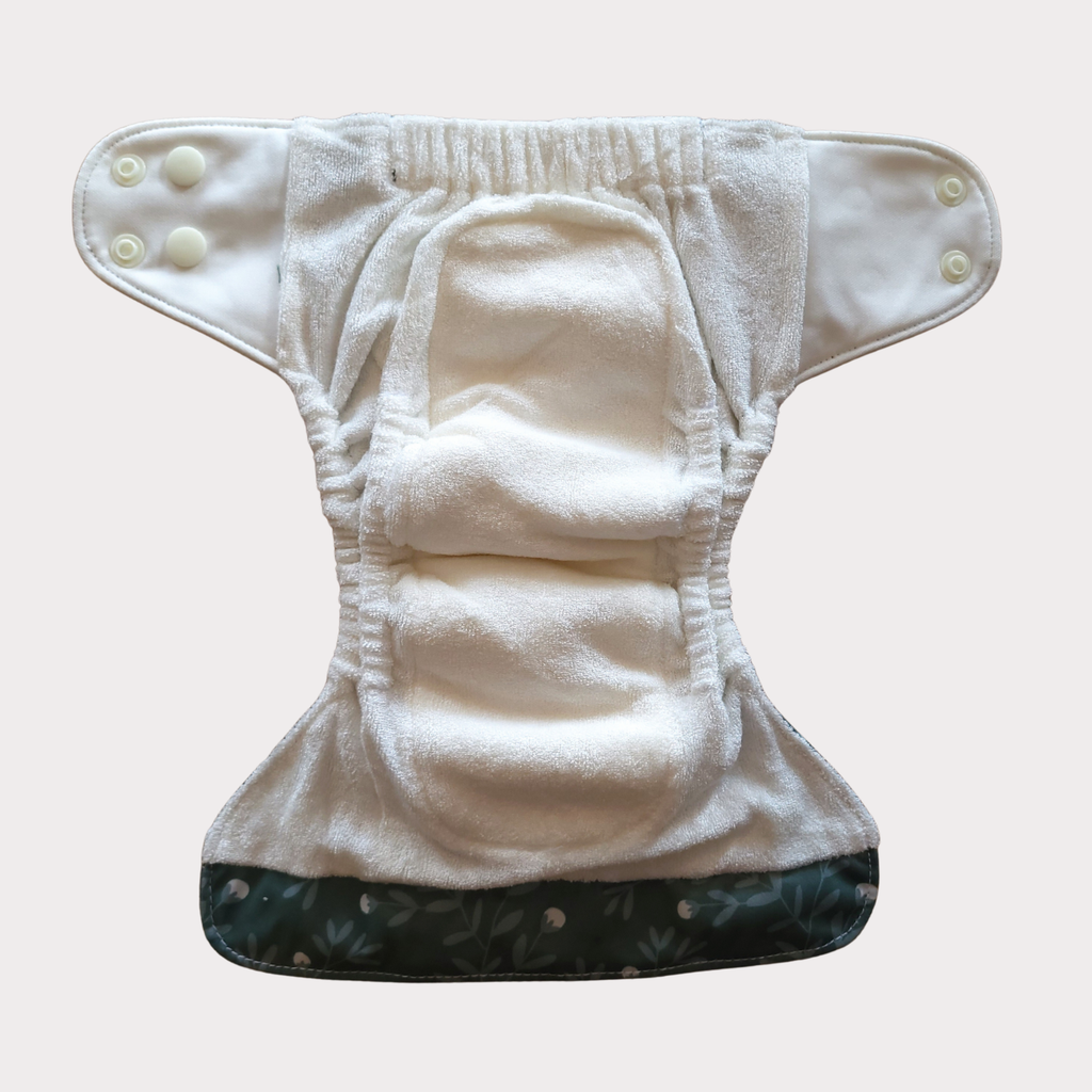 The newborn nappy opened out, showing the soft bamboo terry inside and the sewn-in insert.
