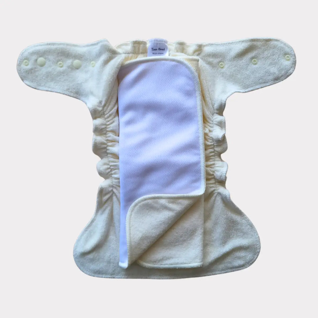 En öppen gräddfärgad tygblöja med en vit absorberande insats.