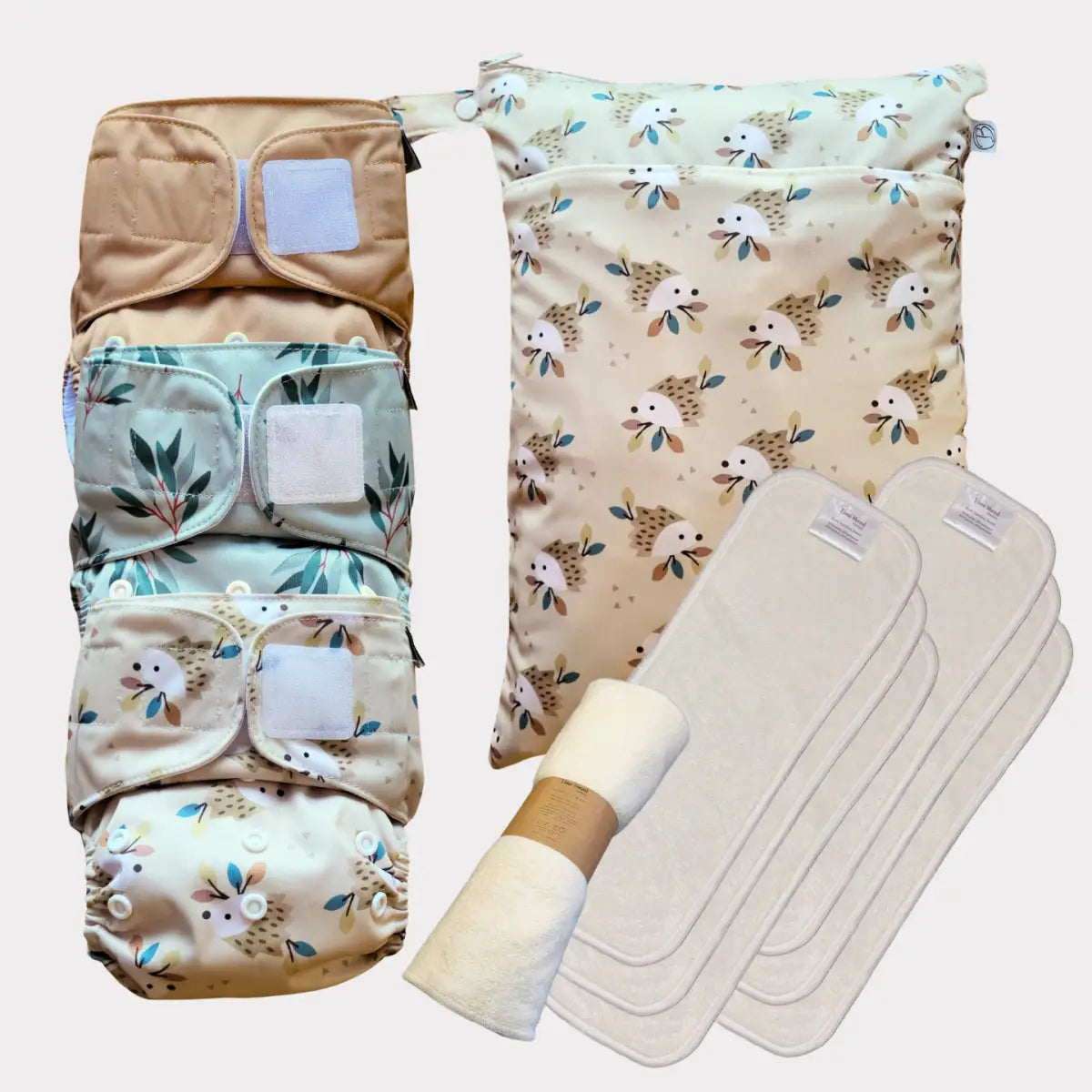 Sats med fyra återanvändbara tygblöjor med mjuka, naturinspirerade mönster i beige och mintgröna toner.