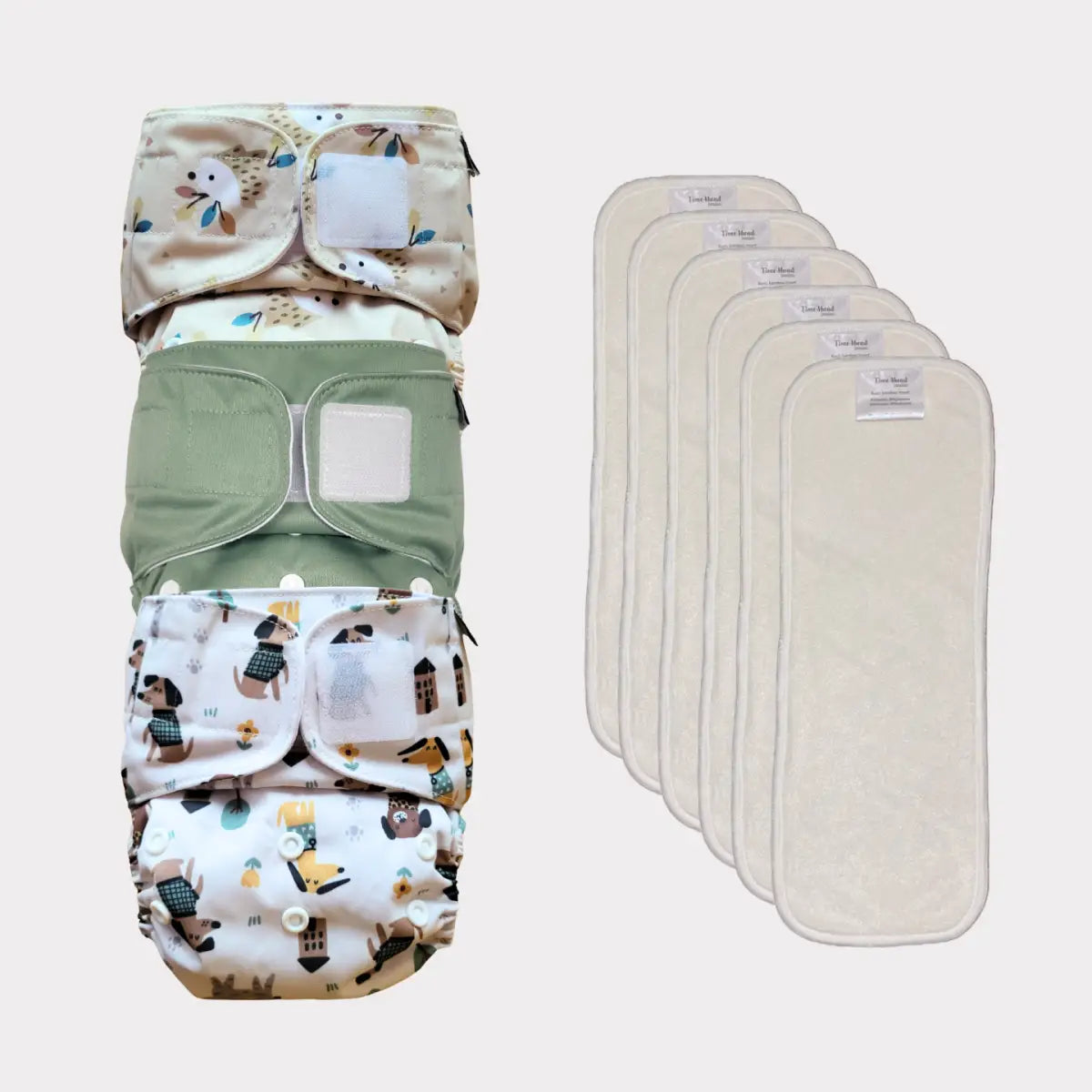 Återanvändbart tygblöjs-set med ett mönstrat fodral och sex insatser, med naturliga färger som beige och kräm.