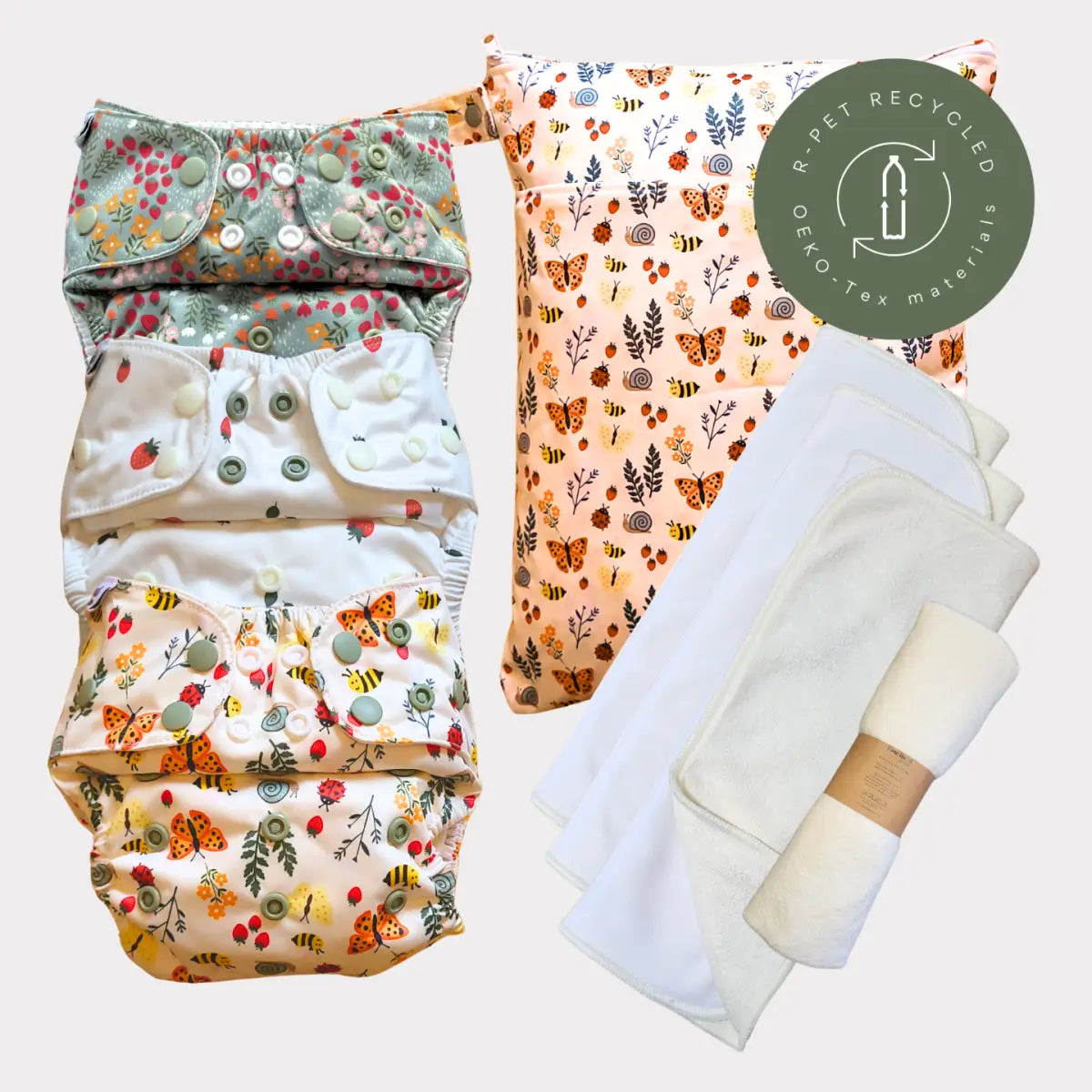 Ett set med fyra färgglada, mönstrade tygblöjor med knäppningsstängningar och matchande tyginlägg.