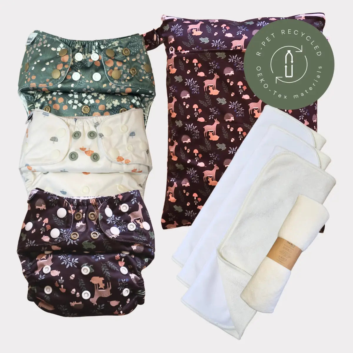 Sats med tre återanvändbara tygblöjor med skogs djurtryck i gröna, krämfärgade och mörk lila mönster, med knäppningsstängningar.