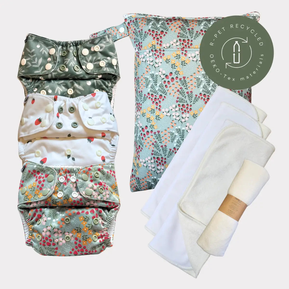 Ett set med fyra blöjor i tyg med blommönster i mjuk grön, vit och pastelltoner med knäppningsknappar.