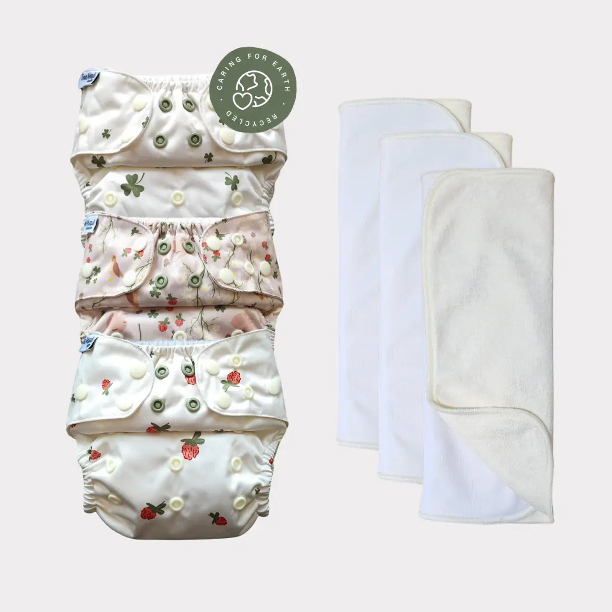 Staplad tygblöjor med blommönster och knäppningsknappar i mjuka pastelltoner.