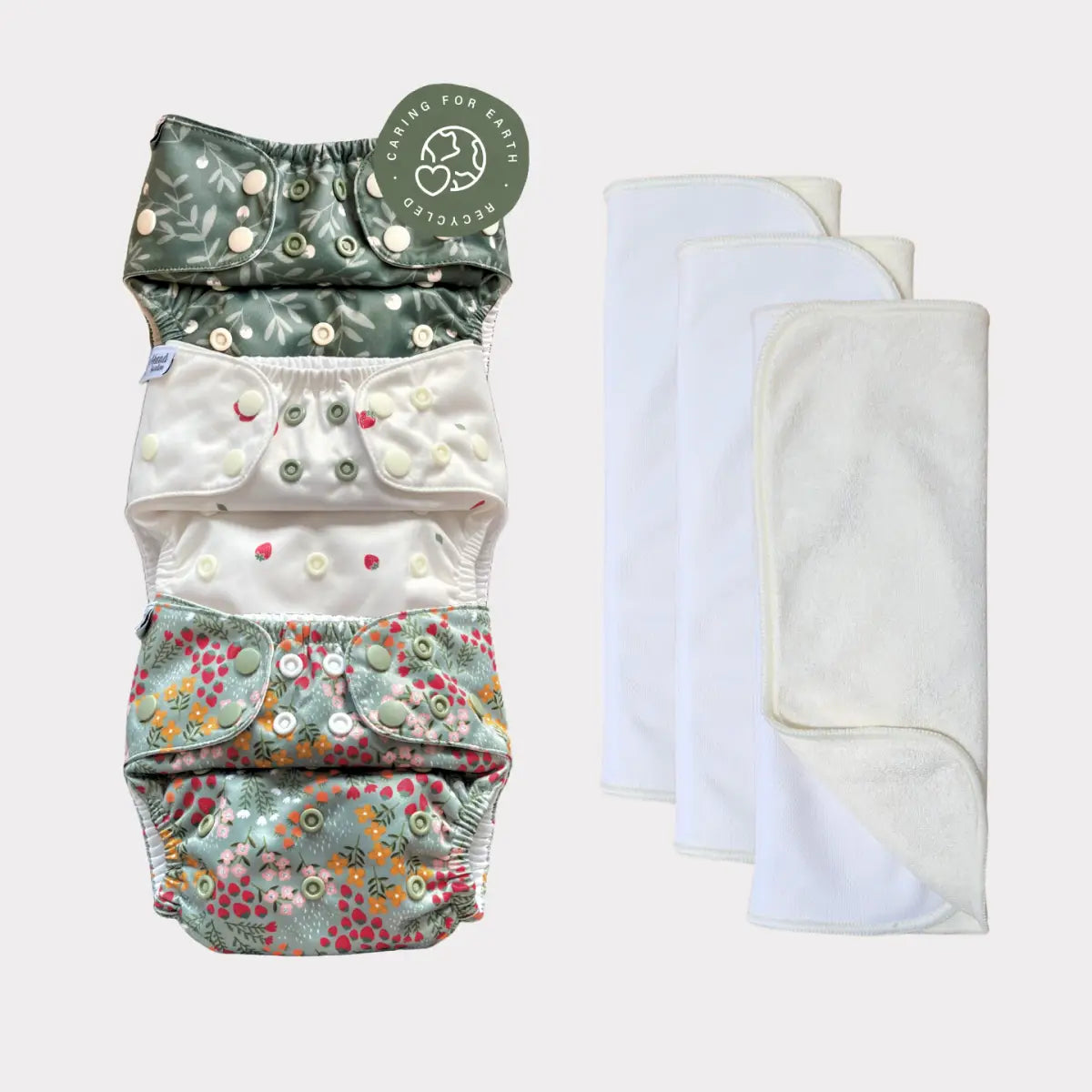 Sats med fyra blöjor i tyg med blommönster, knäppningar och matchande vita absorbenter.