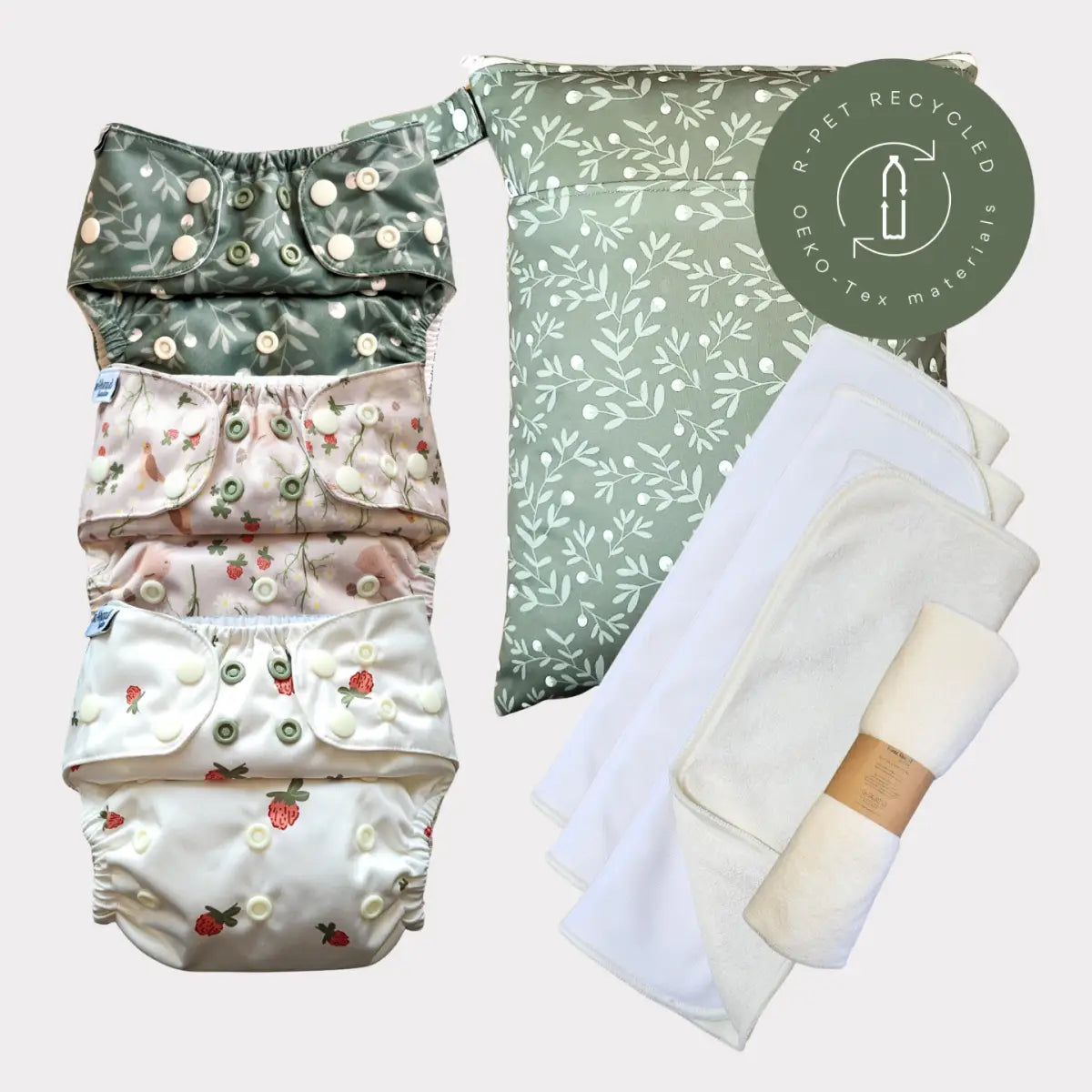 Sats av fyra återanvändbara tygblöjor med blommönster i dämpade gröna, rosa och krämfärgade toner, med tryckknäppningar och mjuk tyg.