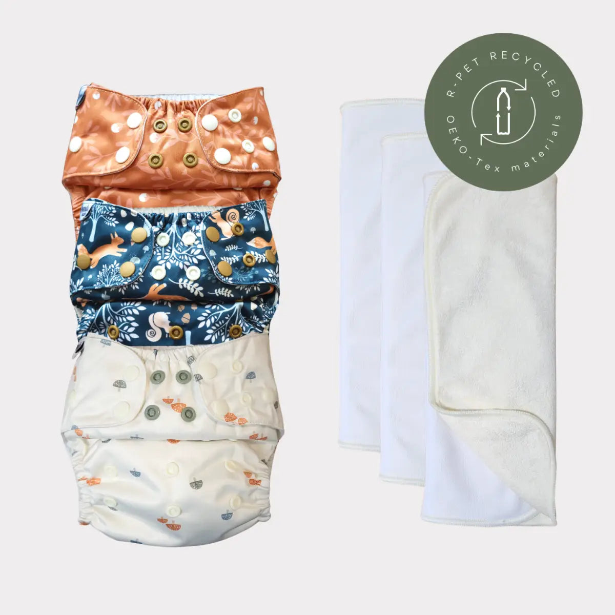 Återanvändbart tygblöjs-set med orange, blå blommönster och vita inlägg.