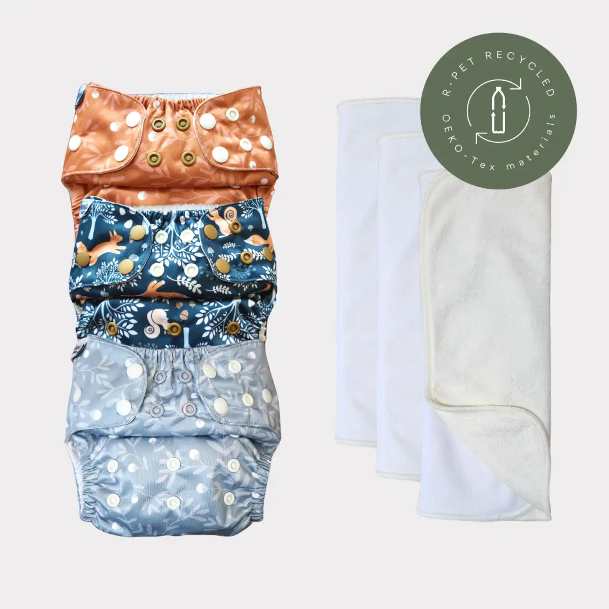 Miljövänliga återanvändbara tygblöjor med färgglada mönster och knappar, tillverkade av hållbara material.