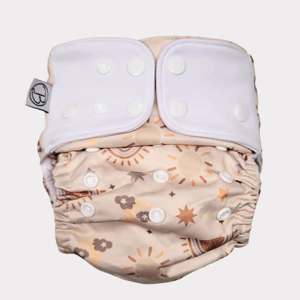 En återanvändbar tygblöja med ett mönster av solar, regnbågar och moln.