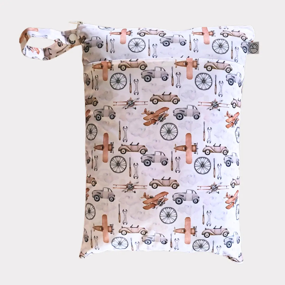 En vit återanvändbar blöjväska med ett lekfullt mönster av vintagebilar, flygplan och cykelhjul i dämpade roséguld- och gråtoner.