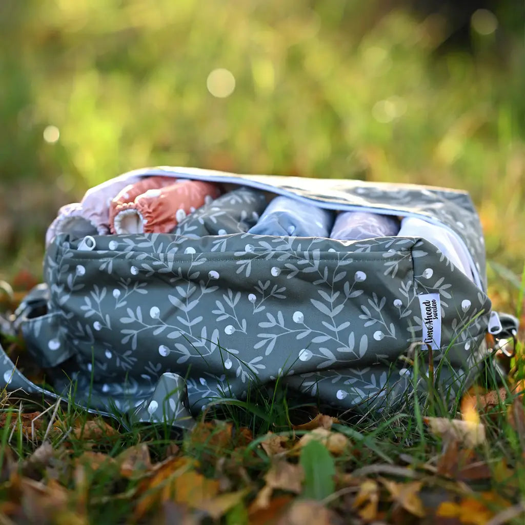 En grön, bladmönstrad våtpåse fylld med olika föremål.