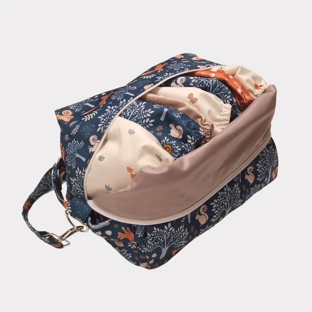 En marinblå duffelväska med ekorre- och trädmönster, delvis uppknäppt för att avslöja ett ljusfärgat foder med liknande mönster.